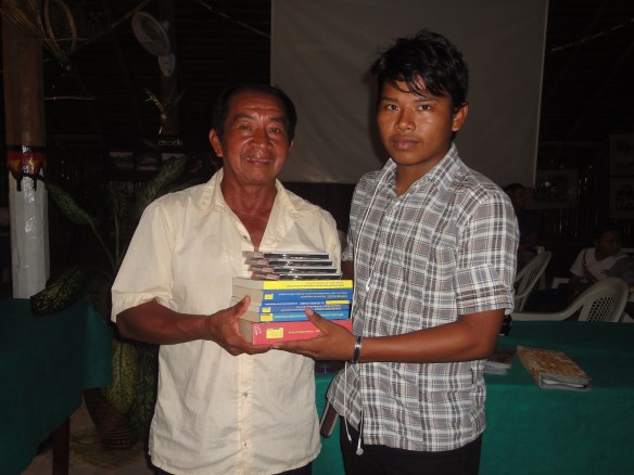 Palestrante Higino Tenório Tuyuka, entrega publicações da FOIRN/ISA ao jovem indígena participante do evento.